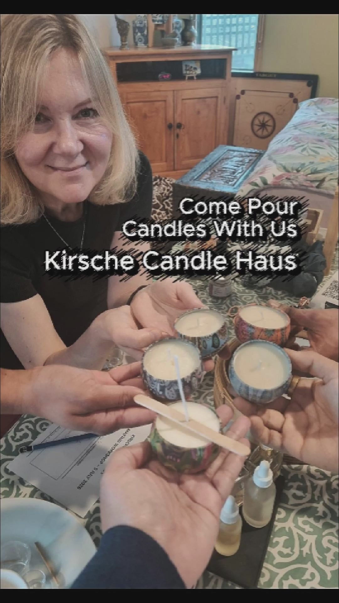 Load video: A group of people sitting around a table looking like they are having an enjoyable time chatting, interacting and making candles. Table is covered with materials to make candles.